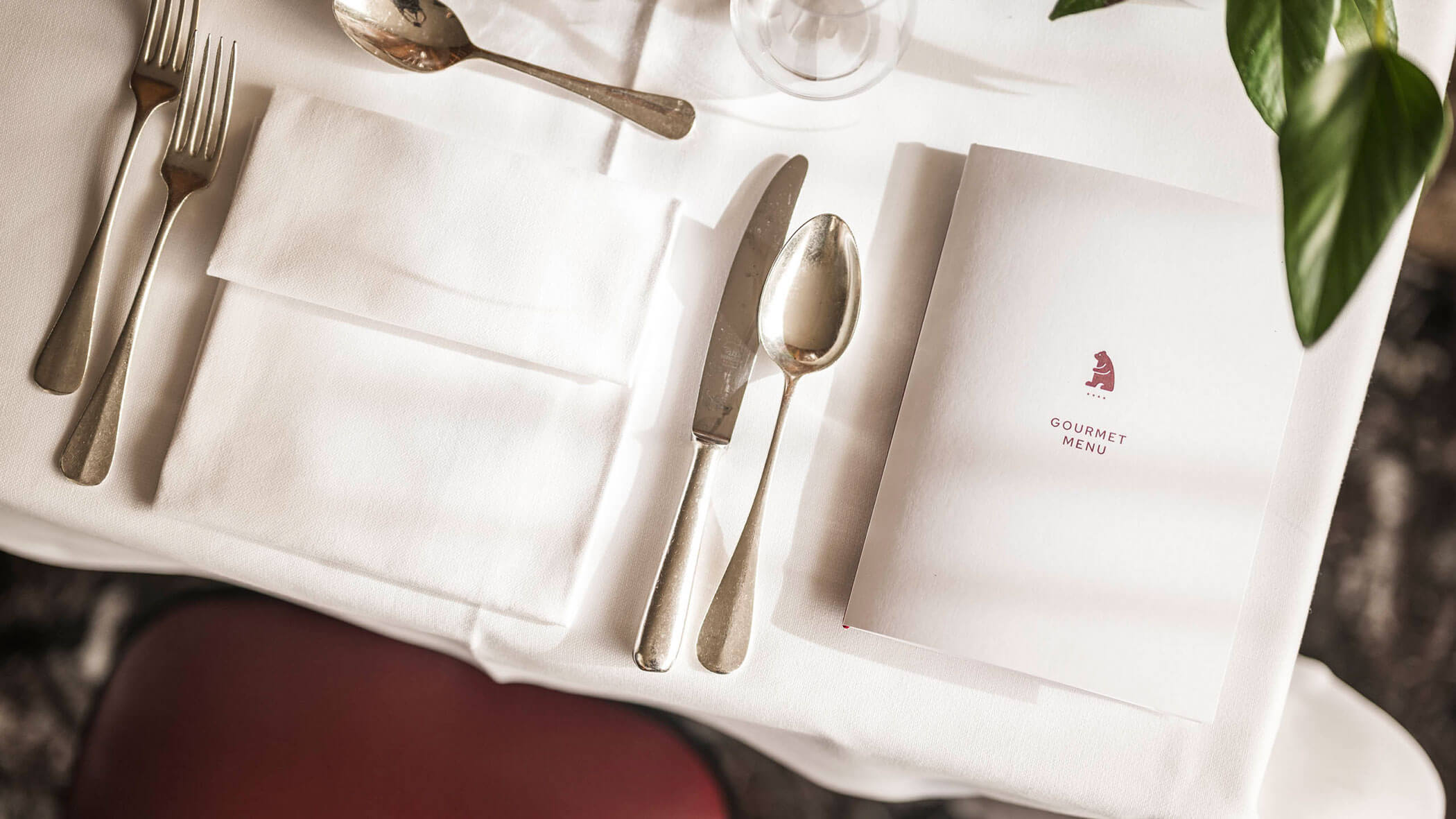 Elegant table setting with silverware, napkin, and a gourmet menu on a white tablecloth.